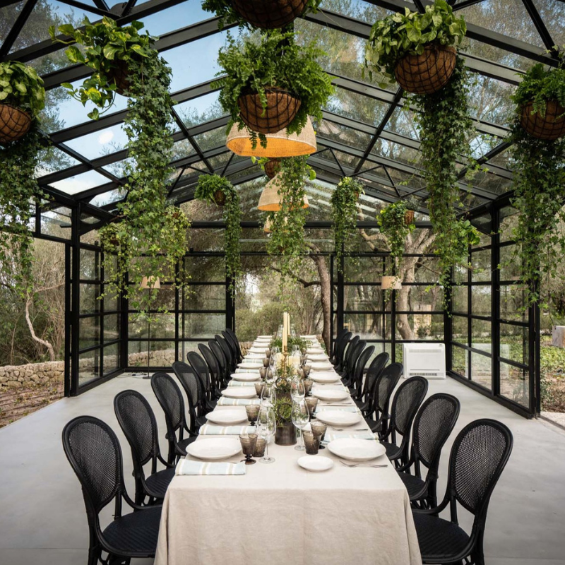 Langbord med middag for firmatur i eksklusive omgivelser med planter og glasshus
